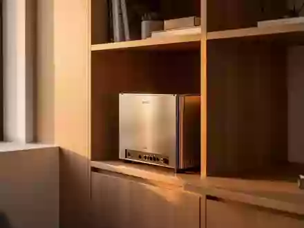 Ein minimalistischer Heimarbeitsplatz mit einem kleinen Netzwerkschrank in einem Holzregal bei warmem Tageslicht. - Foto: über boerse-global.de