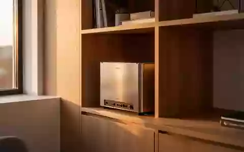 Ein minimalistischer Heimarbeitsplatz mit einem kleinen Netzwerkschrank in einem Holzregal bei warmem Tageslicht. - Foto: über boerse-global.de