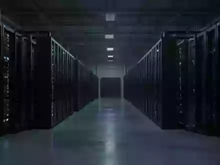 Ein dunkler, industrieller Serverraum mit langen Reihen massiver, unbeschrifteter Serverschränke in einer sterilen Umgebung. - Foto: über boerse-global.de