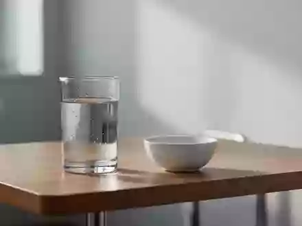 Ein minimalistisch gestalteter medizinischer Untersuchungsraum mit einem Glas Wasser auf einem Holztisch. - Foto: über boerse-global.de