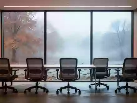 Leerer, minimalistischer Büroraum mit ergonomischen Stühlen vor großen Fenstern und Blick auf eine kühle Herbstlandschaft. - Foto: über boerse-global.de