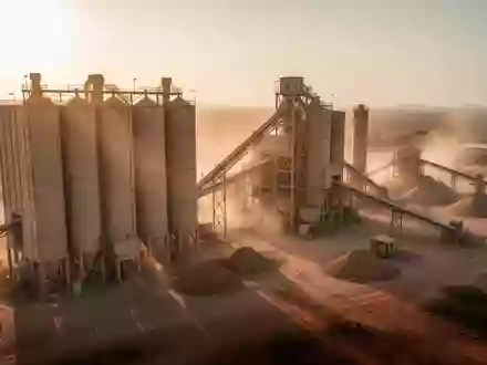 Moderne Zementfabrik mit Silos und Förderbändern bei Sonnenuntergang. - Foto: über boerse-global.de