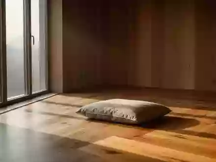 Ein minimalistischer, sonnendurchfluteter Raum mit einem einzelnen Meditationskissen auf einem Holzboden. - Foto: über boerse-global.de