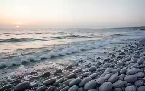 Eine ruhige Küstenlandschaft mit sanfter Brandung und glatten Kieselsteinen an einem Strand bei Tagesanbruch. - Foto: über boerse-global.de