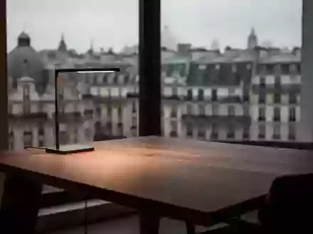 Ein minimalistischer Arbeitsplatz mit einem Holztisch vor einem verschwommenen europäischen Stadtpanorama bei Dämmerung. - Foto: über boerse-global.de