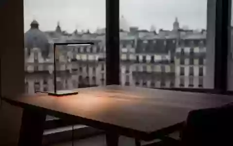 Ein minimalistischer Arbeitsplatz mit einem Holztisch vor einem verschwommenen europäischen Stadtpanorama bei Dämmerung. - Foto: über boerse-global.de