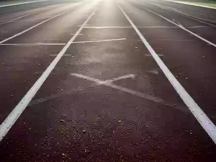 Eine leere, professionelle Leichtathletikbahn in sanftem Morgenlicht mit Fokus auf die Textur der Laufbahn. - Foto: über boerse-global.de