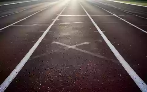 Eine leere, professionelle Leichtathletikbahn in sanftem Morgenlicht mit Fokus auf die Textur der Laufbahn. - Foto: über boerse-global.de