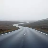 Eine leere, asphaltierte Straße in einer minimalistischen Landschaft bei bewölktem Himmel. - Foto: über boerse-global.de