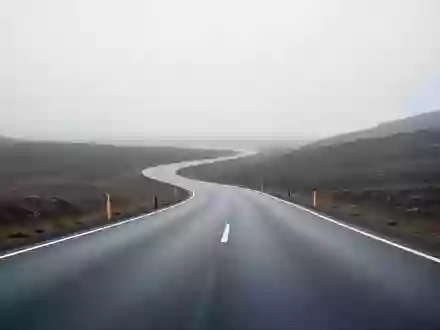 Eine leere, asphaltierte Straße in einer minimalistischen Landschaft bei bewölktem Himmel. - Foto: über boerse-global.de