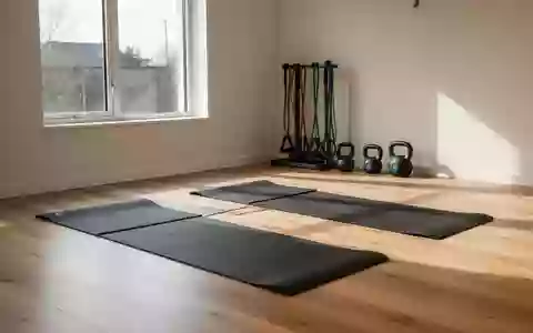 Ein heller, minimalistisch eingerichteter Physiotherapieraum mit Sportmatten und Trainingsgeräten auf einem Holzboden. - Foto: über boerse-global.de