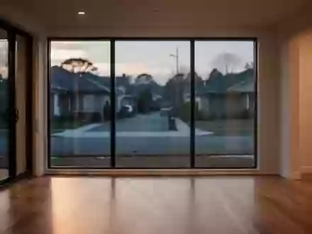 Ein leerer, modern eingerichteter Wohnraum mit großen Fenstern und Blick auf eine ruhige Straße bei Dämmerung. - Foto: über boerse-global.de