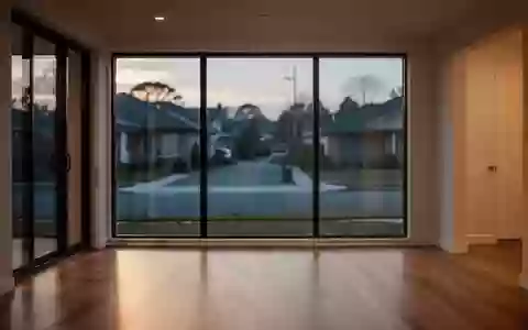 Ein leerer, modern eingerichteter Wohnraum mit großen Fenstern und Blick auf eine ruhige Straße bei Dämmerung. - Foto: über boerse-global.de