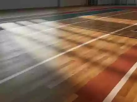 Eine leere, minimalistische Leichtathletikhalle mit poliertem Holzboden und einfallendem Tageslicht. - Foto: über boerse-global.de