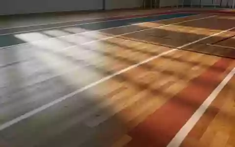 Eine leere, minimalistische Leichtathletikhalle mit poliertem Holzboden und einfallendem Tageslicht. - Foto: über boerse-global.de