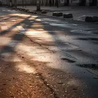 Eine menschenleere, nasse Asphaltstraße bei Morgendämmerung mit langen Schatten und verschwommenen Fahrbahnmarkierungen. - Foto: über boerse-global.de