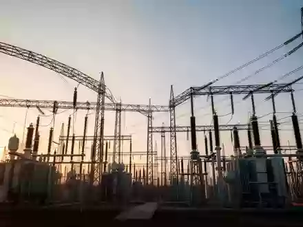 Eine weitläufige industrielle Umspannstation bei Sonnenuntergang mit Hochspannungstransformatoren und Metallgitterstrukturen. - Foto: über boerse-global.de