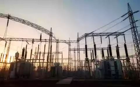 Eine weitläufige industrielle Umspannstation bei Sonnenuntergang mit Hochspannungstransformatoren und Metallgitterstrukturen. - Foto: über boerse-global.de