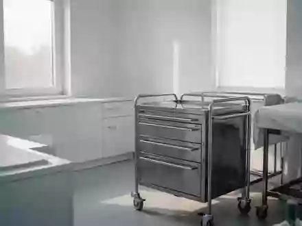 Ein steriler, minimalistischer Behandlungsraum in einer Klinik mit hellem Tageslicht und medizinischem Instrumentenwagen. - Foto: über boerse-global.de
