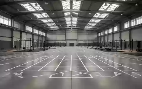 Eine weitläufige, leere Industriehalle mit markierten Laufbahnen und Zonen für funktionelles Training. - Foto: über boerse-global.de