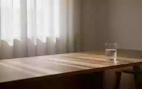 Ein minimalistischer Raum mit weichem Morgenlicht und einem Glas Wasser auf einem Holztisch, der eine ruhige Atmosphäre ausstrahlt. - Foto: über boerse-global.de