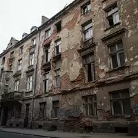 Verfallende Fassade eines Berliner Mietshauses mit bröckelndem Mauerwerk und sichtbaren Bauschäden an einem grauen Tag. - Foto: über boerse-global.de