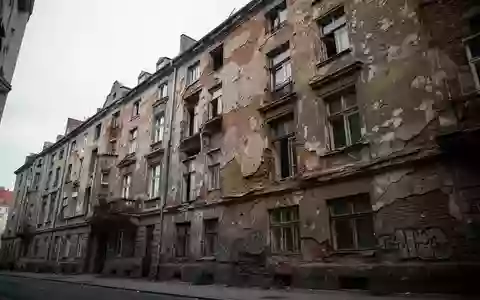 Verfallende Fassade eines Berliner Mietshauses mit bröckelndem Mauerwerk und sichtbaren Bauschäden an einem grauen Tag. - Foto: über boerse-global.de