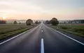 Eine leere, asphaltierte Landstraße in einer ländlichen Umgebung bei Tagesanbruch ohne Schilder oder Fahrzeuge. - Foto: über boerse-global.de