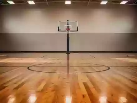 Ein leerer Basketballplatz mit glänzendem Holzboden und einem Korb in einer minimalistischen, hellen Halle. - Foto: über boerse-global.de