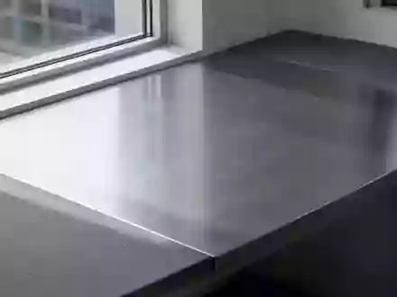 Ein minimalistischer, leerer Industriearbeitstisch aus gebürstetem Aluminium und mattem Verbundmaterial in einem Studio. - Foto: über boerse-global.de