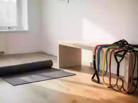 Ein minimalistischer Physiotherapieraum mit einer Yogamatte und Trainingsbändern auf einer Holzbank bei Tageslicht. - Foto: über boerse-global.de