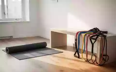 Ein minimalistischer Physiotherapieraum mit einer Yogamatte und Trainingsbändern auf einer Holzbank bei Tageslicht. - Foto: über boerse-global.de