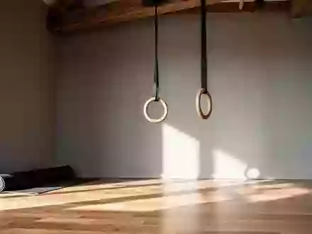 Minimalistisch eingerichteter Trainingsraum mit einer zusammengerollten Yogamatte und einem hängenden Gymnastikring. - Foto: über boerse-global.de