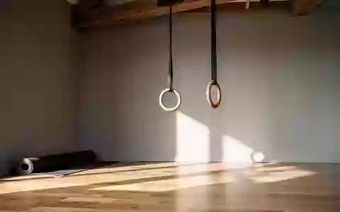 Minimalistisch eingerichteter Trainingsraum mit einer zusammengerollten Yogamatte und einem hängenden Gymnastikring. - Foto: über boerse-global.de