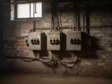Verstaubte elektrische Sicherungskästen und Leitungen an einer alten Backsteinwand in einem Keller. - Foto: über boerse-global.de