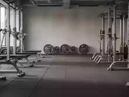 Ein minimalistisches, leeres Fitnessstudio mit hochwertigen Kraftgeräten und Hantelscheiben im Hintergrund. - Foto: über boerse-global.de