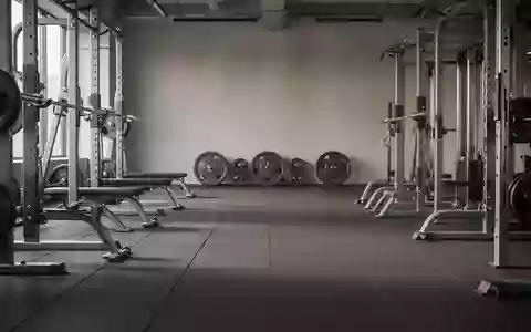 Ein minimalistisches, leeres Fitnessstudio mit hochwertigen Kraftgeräten und Hantelscheiben im Hintergrund. - Foto: über boerse-global.de
