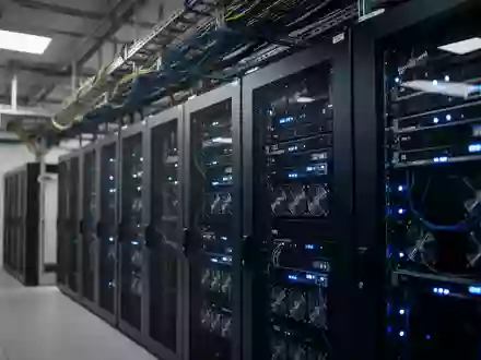 Ein moderner Serverraum mit Reihen von dunklen Serverschränken und blauen Statusleuchten in einer industriellen Umgebung. - Foto: über boerse-global.de