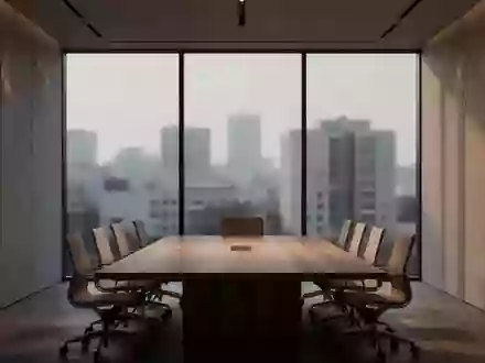 Ein leerer, modern gestalteter Konferenzraum mit einem Holztisch vor einer Fensterfront bei Dämmerung. - Foto: über boerse-global.de