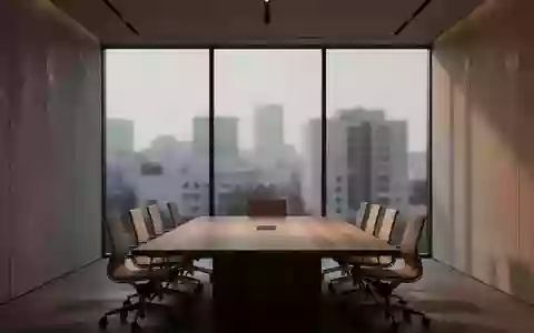 Ein leerer, modern gestalteter Konferenzraum mit einem Holztisch vor einer Fensterfront bei Dämmerung. - Foto: über boerse-global.de