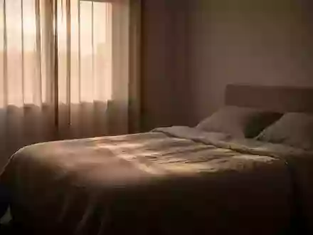Ein minimalistisch eingerichtetes, ruhiges Schlafzimmer bei Tagesanbruch mit einem unbenutzten Bett und natĂĽrlichem Licht. - Foto: ĂĽber boerse-global.de