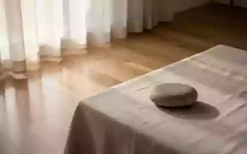 Ein minimalistisch gestalteter Raum mit weichem Tageslicht, das auf einen einzelnen glatten Flussstein auf einer Leinenoberfläche fällt. - Foto: über boerse-global.de