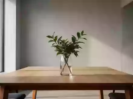 Ein minimalistischer, heller Büroarbeitsplatz mit einem leeren Holztisch und einer Pflanze vor einer neutralen Wand. - Foto: über boerse-global.de