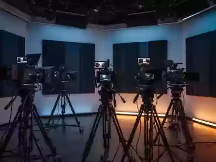 Ein modernes, minimalistisches Fernsehstudio mit professioneller Aufnahmetechnik in einer abendlichen, atmosphärischen Beleuchtung. - Foto: über boerse-global.de