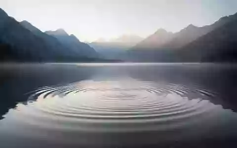 Eine ruhige Bergseeoberfläche bei Sonnenaufgang, die Rhythmus und Ausgeglichenheit symbolisiert. - Foto: über boerse-global.de