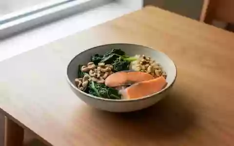 Eine Nahaufnahme einer ausgewogenen Mahlzeit mit grĂĽnem GemĂĽse, NĂĽssen und Lachs auf einem schlichten Holztisch bei Tageslicht. - Foto: ĂĽber boerse-global.de