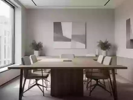 Ein minimalistisch gestalteter Besprechungsraum mit zwei leeren StĂŒhlen an einem Holztisch bei Tageslicht. - Foto: ĂŒber boerse-global.de