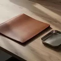 Ein minimalistischer Holzschreibtisch mit einer leeren Dokumentenmappe und einer Metallschale in natürlichem Licht. - Foto: über boerse-global.de