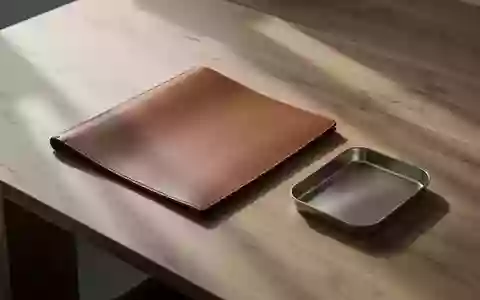 Ein minimalistischer Holzschreibtisch mit einer leeren Dokumentenmappe und einer Metallschale in natürlichem Licht. - Foto: über boerse-global.de