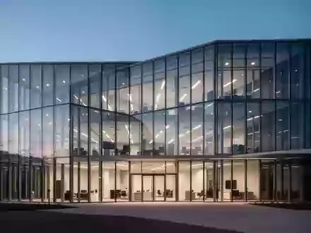 Moderne Büroarchitektur mit Glasfassade bei Dämmerung, symbolisiert betriebliche Investitionen und Unternehmensverwaltung. - Foto: über boerse-global.de